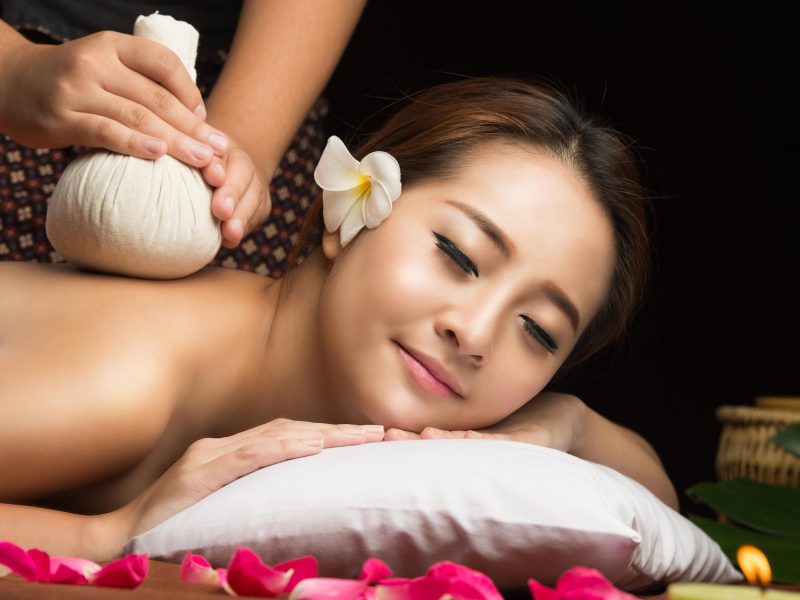 Asian woman getting thai herbal compress massage in spa.She is v