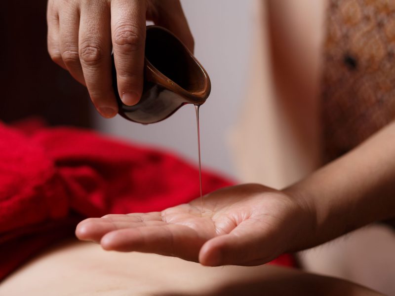 close-up of the masseur's hands, a drop of massage oil flows dow